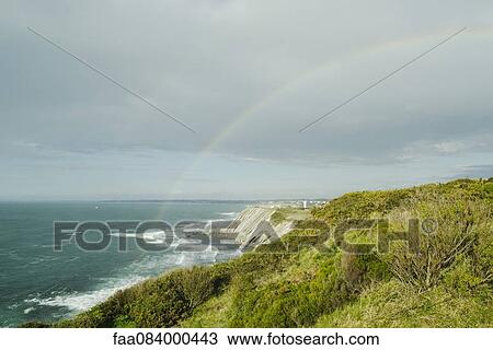 Stock Image - Rainbow on the cliffs of Ciboure, France. Fotosearch