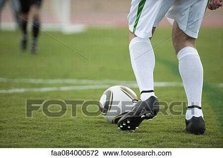Stock Image - Soccer player preparing to kick soccer ball, cropped. Fotosearch