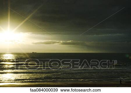 Stock Photo - Sunset over the Atlantic Ocean, ship on the horizon, Ondres France. Fotosearch