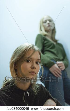 Teenage girl looking at camera, friend in background View Large Photo Image Stock Photograph - Teenage girl looking at camera, friend in background. Fotosearch