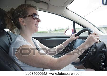 Stock Image - Woman driving car, smiling. Fotosearch