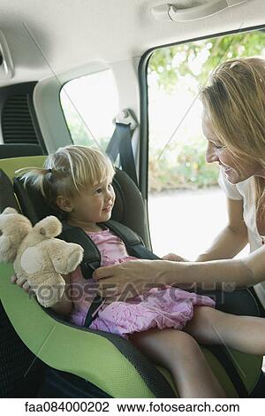 Woman fastening little girl into car seat View Large Photo Image Stock Image - Woman fastening little girl into car seat. Fotosearch