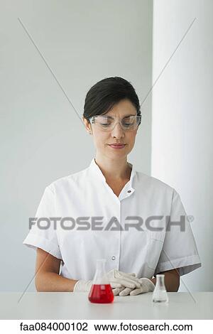 Woman looking at laboratory flasks filled with liquid View Large Photo Image Stock Image - Woman looking at laboratory flasks filled with liquid. Fotosearch