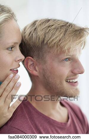 Stock Photo - Woman whispering in man's ear. Fotosearch