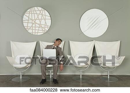 Young businessman fell asleep in chair with laptop computer on lap View Large Photo Image Stock Photo - Young businessman fell asleep in chair with laptop computer on lap. Fotosearch