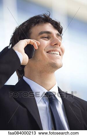 Young executive talking on cell phone, smiling View Large Photo Image Stock Image - Young executive talking on cell phone, smiling. Fotosearch