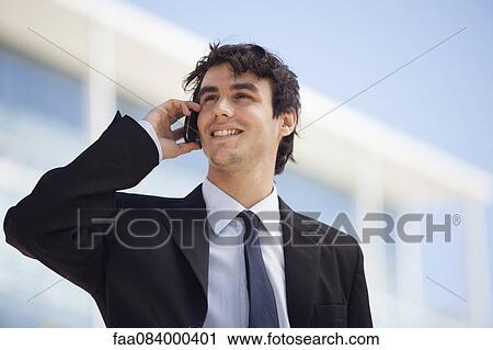 Young executive talking on cell phone outdoors View Large Photo Image Stock Image - Young executive talking on cell phone outdoors. Fotosearch