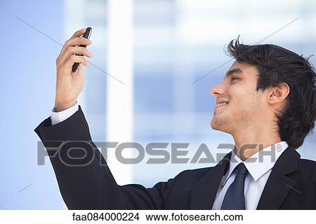 Young executive video calling on cell phone outdoors View Large Photo Image Picture - Young executive video calling on cell phone outdoors. Fotosearch