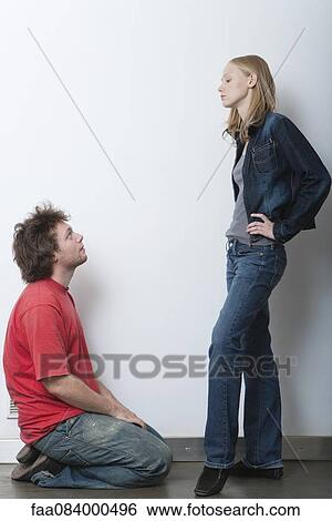 Young man kneeling in front of angry girlfriend View Large Photo Image Stock Photograph - Young man kneeling in front of angry girlfriend. Fotosearch