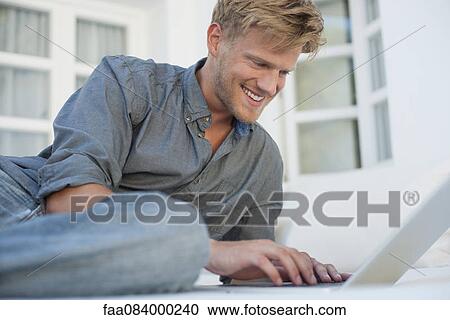Young man using laptop computer outdoors View Large Photo Image Stock Image - Young man using laptop computer outdoors. Fotosearch