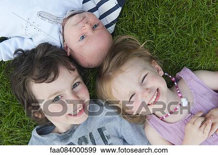 Young siblings lying on grass, portrait View Large Photo Image Stock Photo - Young siblings lying on grass, portrait. Fotosearch