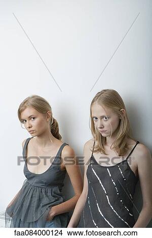 Young woman and teenage girl leaning against wall, looking warily at camera View Large Photo Image Picture - Young woman and teenage girl leaning against wall, looking warily at camera. Fotosearch