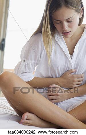 Young woman clutching stomach in pain View Large Photo Image Stock Image - Young woman clutching stomach in pain. Fotosearch