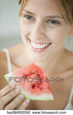 Stock Image - Young woman eating watermelon, portrait. Fotosearch