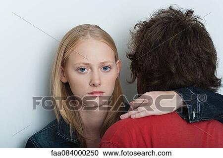 Young woman embracing man, looking at camera with serious expression View Large Photo Image Stock Image - Young woman embracing man, looking at camera with serious expression. Fotosearch