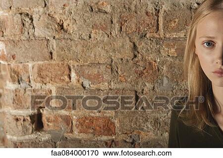 Young woman in front of brick wall, cropped portrait View Large Photo Image Stock Image - Young woman in front of brick wall, cropped portrait. Fotosearch