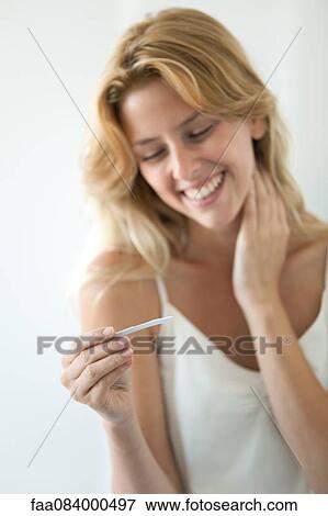 Young woman looking at pregnancy test, smiling View Large Photo Image Stock Photo - Young woman looking at pregnancy test, smiling. Fotosearch