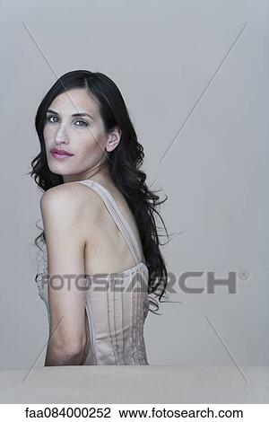 Stock Image - Young woman looking over shoulder, portrait. Fotosearch