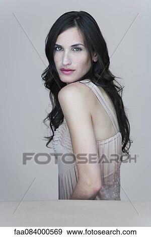 Stock Photo - Young woman looking over shoulder, portrait. Fotosearch
