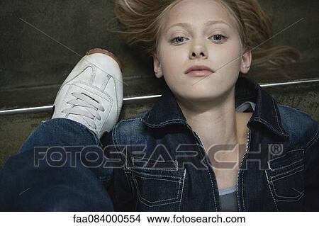 Young woman lying on ground beside someone's shoe, portrait View Large Photo Image Picture - Young woman lying on ground beside someone's shoe, portrait. Fotosearch