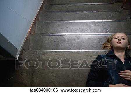 Stock Photograph - Young woman lying on stairs, portrait. Fotosearch