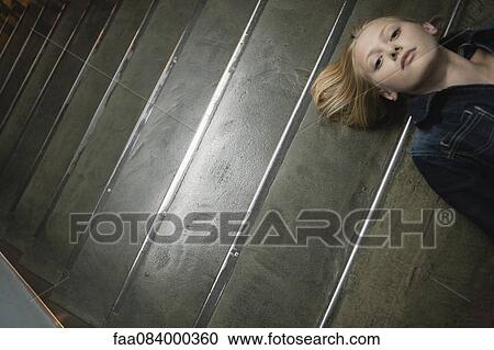 Stock Image - Young woman lying on stairs. Fotosearch