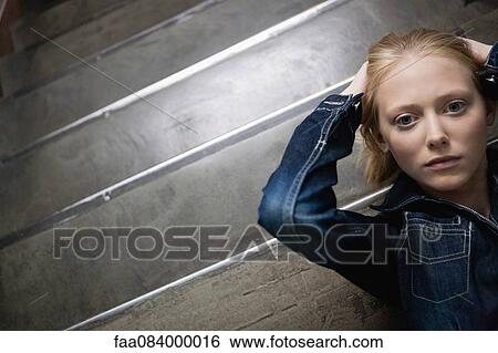 Young woman lying on stairs with hands behind head, portrait View Large Photo Image Stock Photograph - Young woman lying on stairs with hands behind head, portrait. Fotosearch