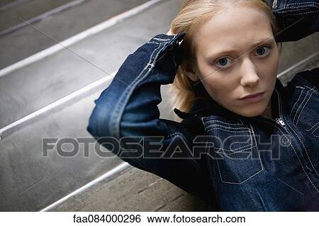 Young woman lying on stairs with hands behind head, portrait View Large Photo Image Stock Photograph - Young woman lying on stairs with hands behind head, portrait. Fotosearch