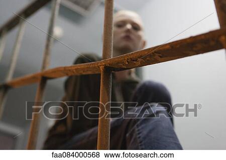 Young woman sitting alone, focus on railing in foreground View Large Photo Image Stock Photo - Young woman sitting alone, focus on railing in foreground. Fotosearch