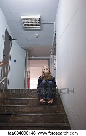 Young woman sitting alone on stairs View Large Photo Image Stock Photograph - Young woman sitting alone on stairs. Fotosearch
