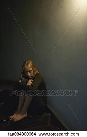 Young woman sitting on stairs, hugging knees View Large Photo Image Picture - Young woman sitting on stairs, hugging knees. Fotosearch