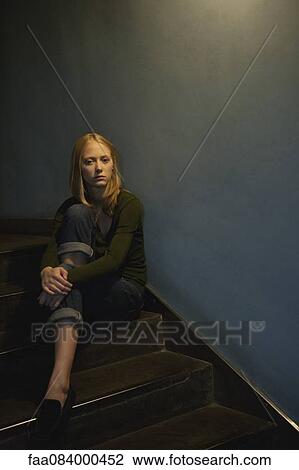 Young woman sitting on stairs, hugging knee View Large Photo Image Stock Image - Young woman sitting on stairs, hugging knee. Fotosearch