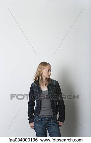 Young woman standing with hands in pockets, looking away View Large Photo Image Stock Photograph - Young woman standing with hands in pockets, looking away. Fotosearch
