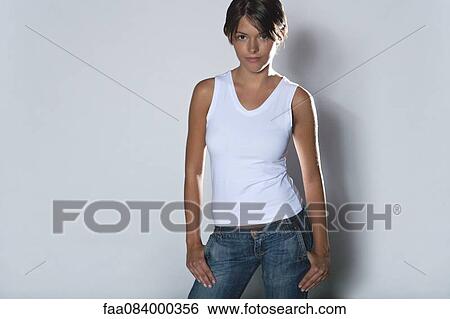 Young woman standing with hands in pockets, portrait View Large Photo Image Stock Photograph - Young woman standing with hands in pockets, portrait. Fotosearch