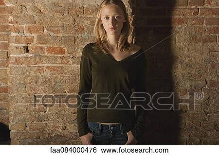 Stock Photograph - Young woman standing with hands in pockets, portrait. Fotosearch