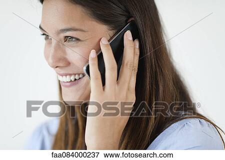Stock Photo - Young woman talking on cell phone, smiling. Fotosearch