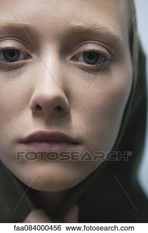 Stock Photograph - Young woman wearing hood, close-up portrait. Fotosearch