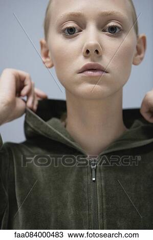 Stock Image - Young woman wearing hooded sweatshirt, portrait. Fotosearch