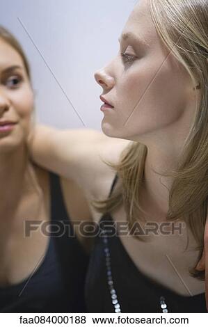 Stock Photo - Young woman with arm around girlfriend's shoulder. Fotosearch