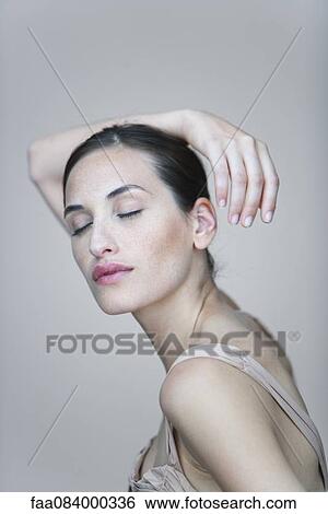 Young woman with arm resting on head, eyes closed, portrait View Large Photo Image Stock Photograph - Young woman with arm resting on head, eyes closed, portrait. Fotosearch