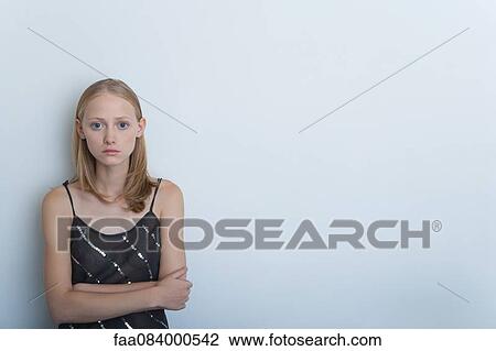 Stock Image - Young woman with arms folded, portrait. Fotosearch