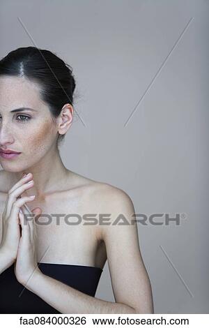Stock Photograph - Young woman with clasped hands, cropped portrait. Fotosearch