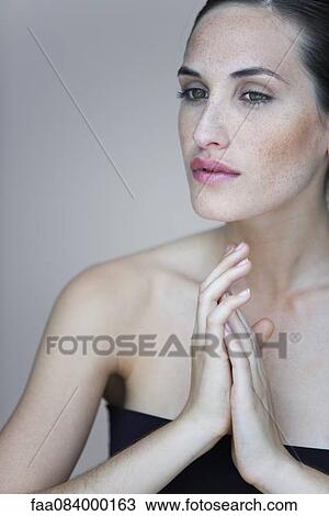 Young woman with hands clasped in front of chest, portrait View Large Photo Image Stock Image - Young woman with hands clasped in front of chest, portrait. Fotosearch