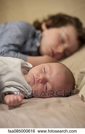 Stock Photograph - Baby and older brother sleeping side by side. Fotosearch