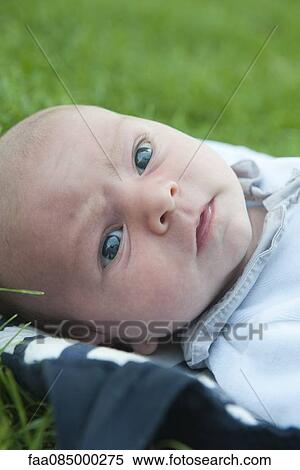 Stock Photography - Baby boy lying on grass, portrait. Fotosearch