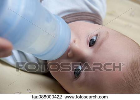 Stock Image - Baby drinking from baby bottle, close-up. Fotosearch