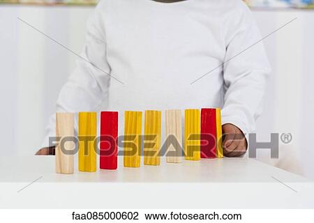 Stock Image - Baby lining up blocks, mid section. Fotosearch