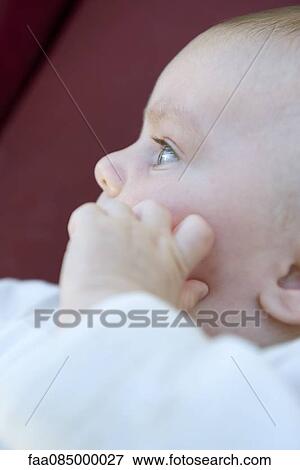 Stock Photo - Baby with hand on face, side view. Fotosearch