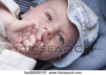 Stock Photo - Baby with hands in mouth, high angle view. Fotosearch