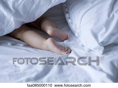 Stock Image - Baby's barefeet under duvet, cropped. Fotosearch
